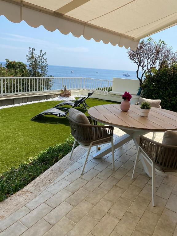 un patio avec une table et des chaises et l'océan dans l'établissement Cap d.Azur, à Roquebrune-Cap-Martin