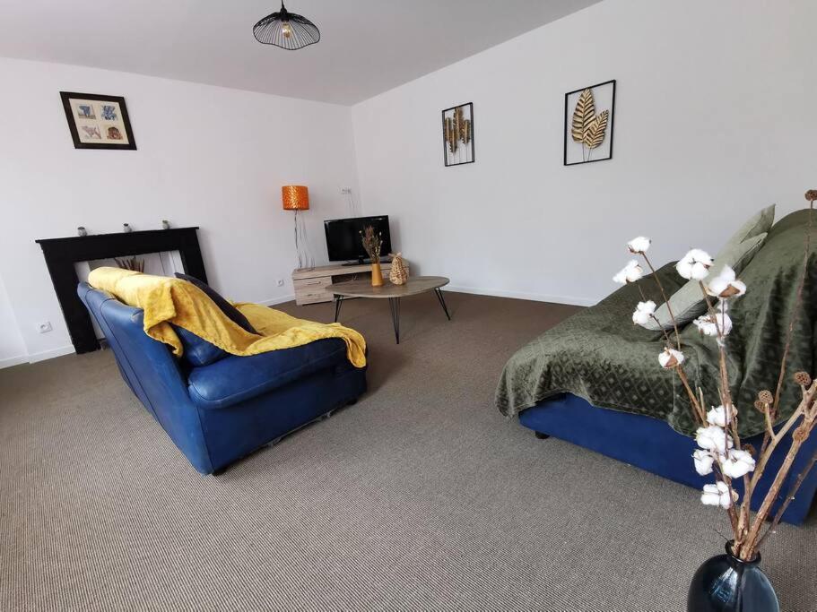 a living room with a blue couch and a bed at La halte cycliste in Domfront