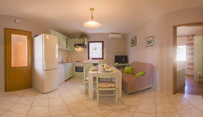 a kitchen and living room with a refrigerator and a table at Apartment s Jukica in Vis
