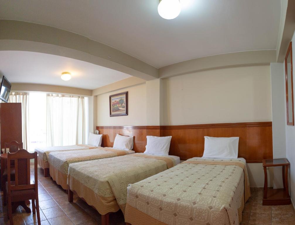 a hotel room with three beds in a room at Takana Inn in Tacna