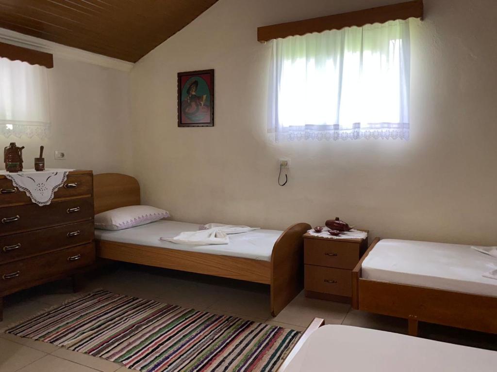 a bedroom with two beds and a dresser and a window at Kasaj Villa in Gjirokastër