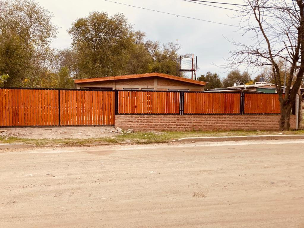 a house with a wooden fence and a building at cabaña Palmira in Santa Rosa de Calamuchita