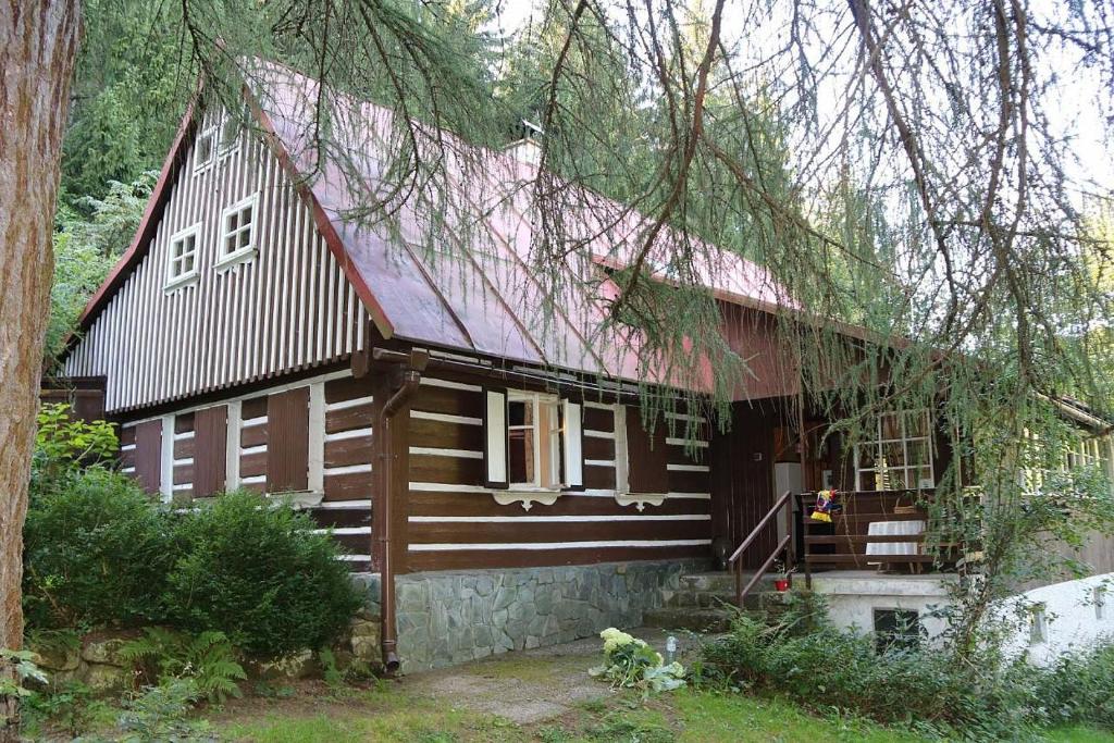 ein großes Holzhaus mit rotem Dach in der Unterkunft Chalupa pod Modřínem in Kořenov