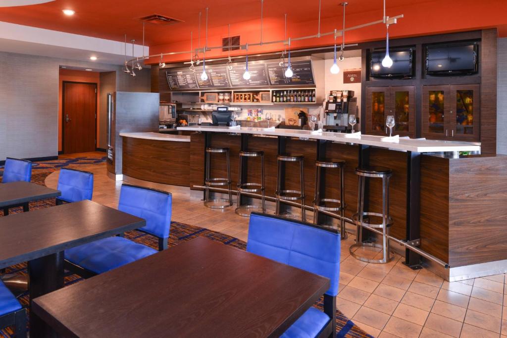 a restaurant with tables and blue chairs and a bar at Courtyard Pittsburgh Monroeville in Monroeville
