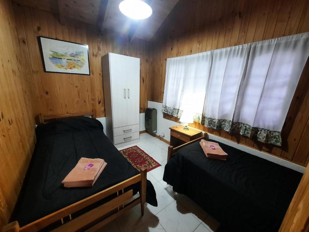 Habitación pequeña con 2 camas y ventana en Cabaña Ayelen en Esquel