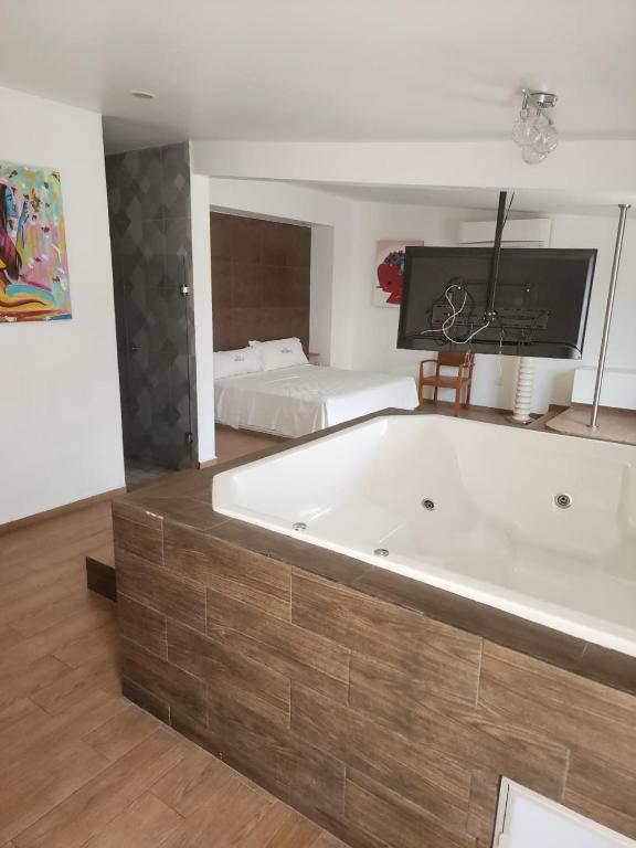 グアダラハラにあるMOTEL PREMIERのベッド付きの客室内に白い大型バスタブが備わります。