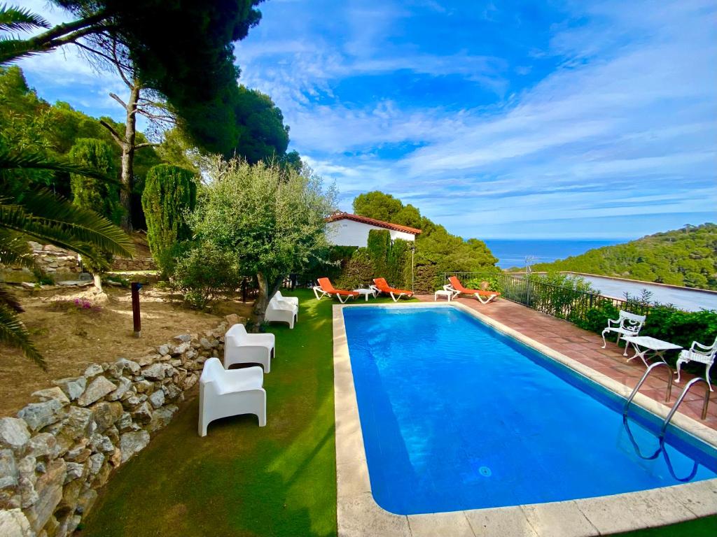 a swimming pool in a yard with white furniture and the ocean at Villa Buda Begur in Begur