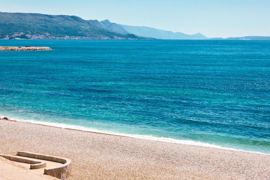 een strand met blauw water en bergen op de achtergrond bij Apartments Zenta in Split