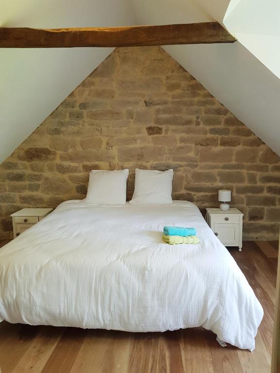 - une chambre avec un lit blanc et un mur en briques dans l'établissement HAMEAU DE LEIGNOUA, au Saint