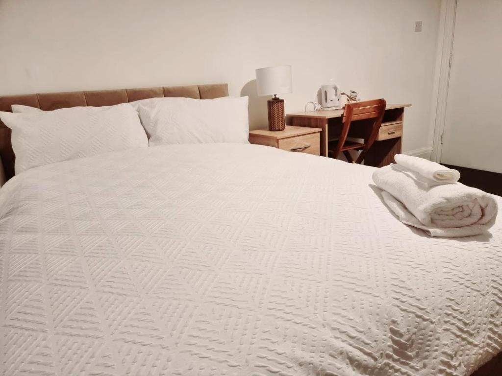 a bedroom with a white bed with towels on it at Lilies Lodge in Balby