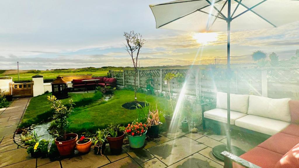 a patio with a garden with plants and an umbrella at Liverpool - Cosy Jazzy Beach Home! in Waterloo