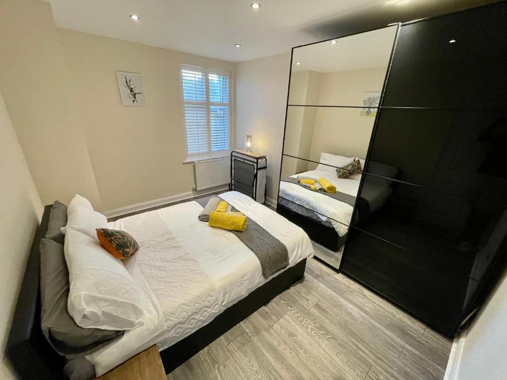 a bedroom with two beds and a large mirror at Paul Properties in Ruislip