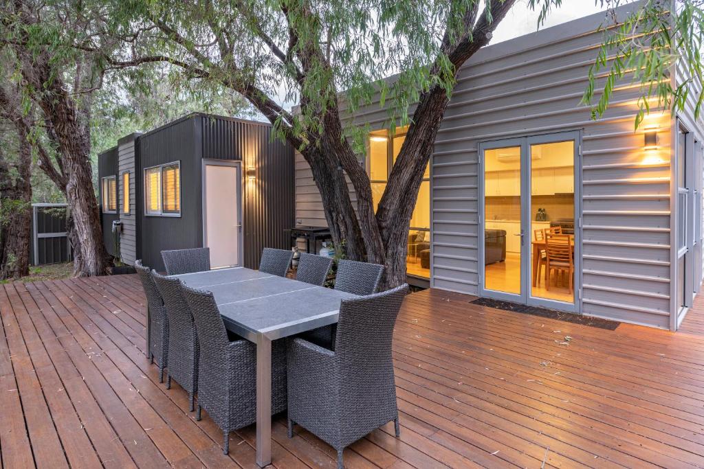 a house with a table and chairs on a deck at Whatmans Beach House - on the water's edge in Dunsborough