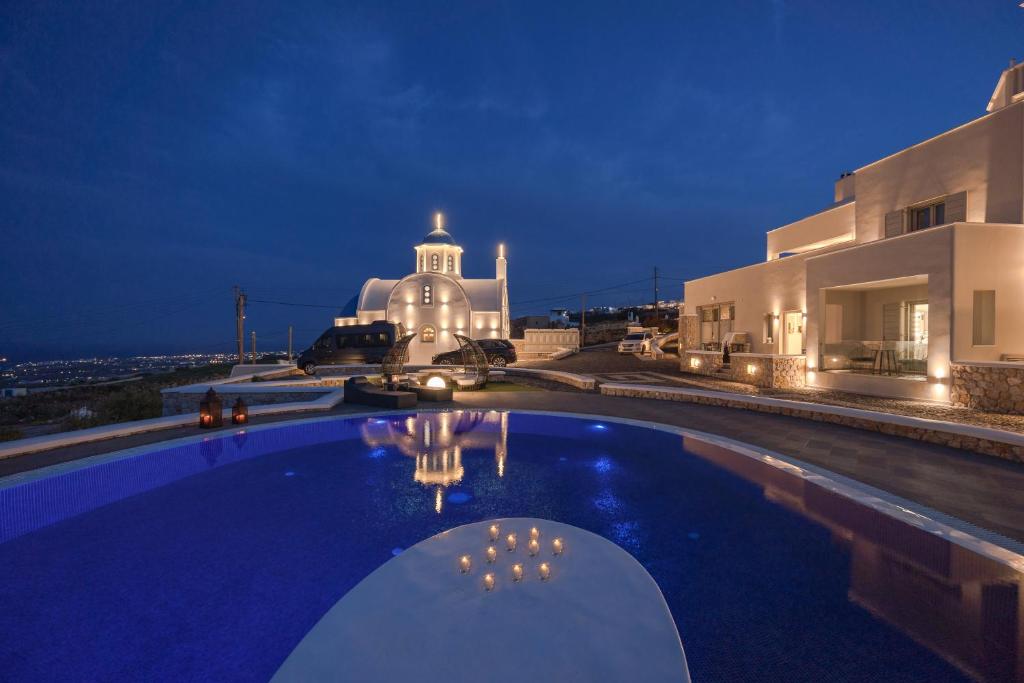 a swimming pool in front of a house at night at SANTORINI GRAND LUXURY VILLAS in Imerovigli