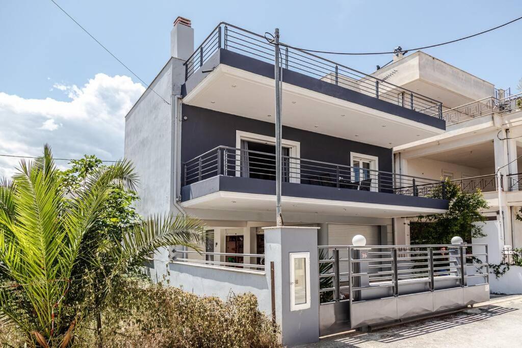 ein weißes Haus mit einem Balkon und Palmen in der Unterkunft Luxury Beach House in Volos