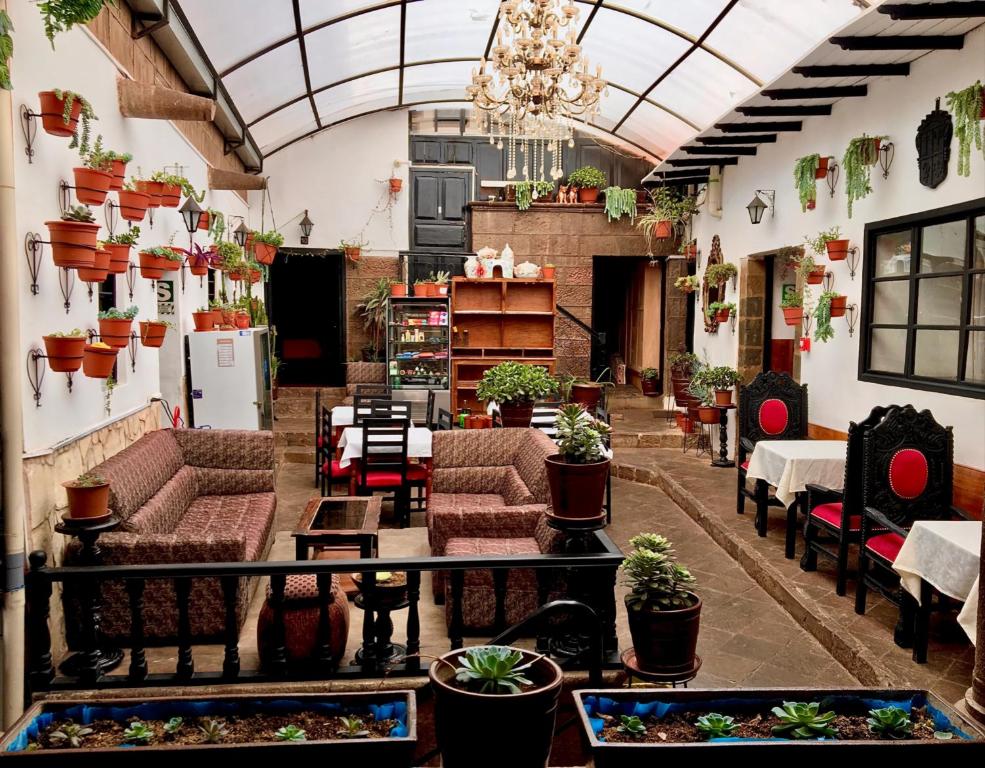 Casona Dorada Hotel Cusco في كوسكو: غرفة كبيرة مع الأرائك والطاولات والنباتات الفخارية