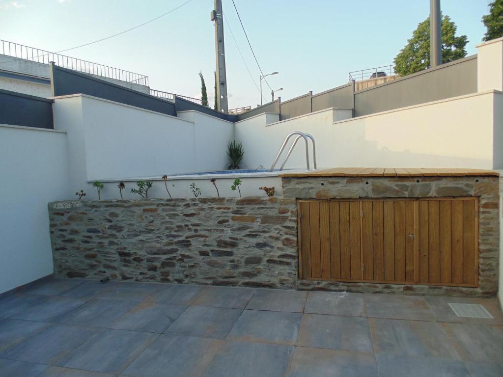 a patio with a stone wall and a wooden door at Casa do Alfaiate - Douro in Peso da Régua