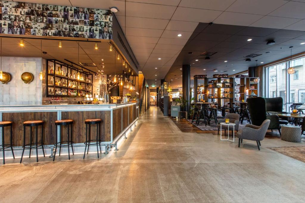 un restaurante con un bar con mesas y sillas en Radisson Blu Metropol Helsingborg, en Helsingborg