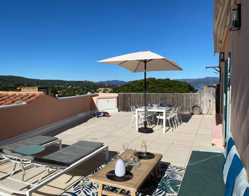 un patio avec un parasol, une table et des chaises dans l'établissement Appartement d'exception, vue Saint-Tropez, à Saint-Tropez