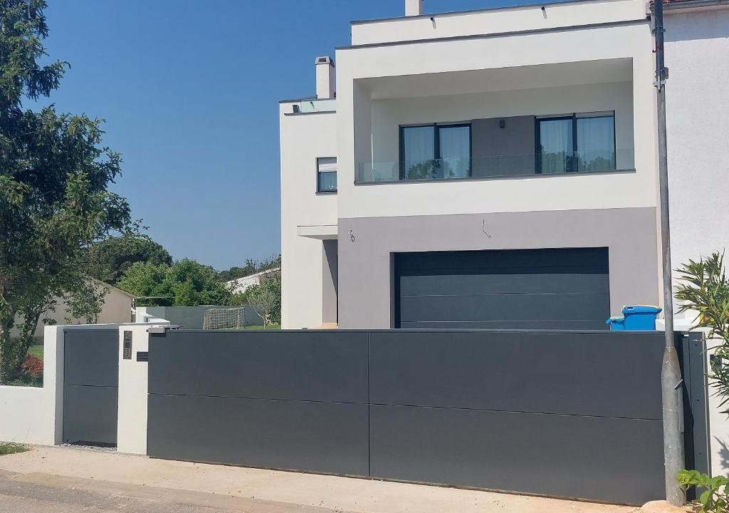 una grande casa bianca con un garage nero di Villa Ulika a Fažana