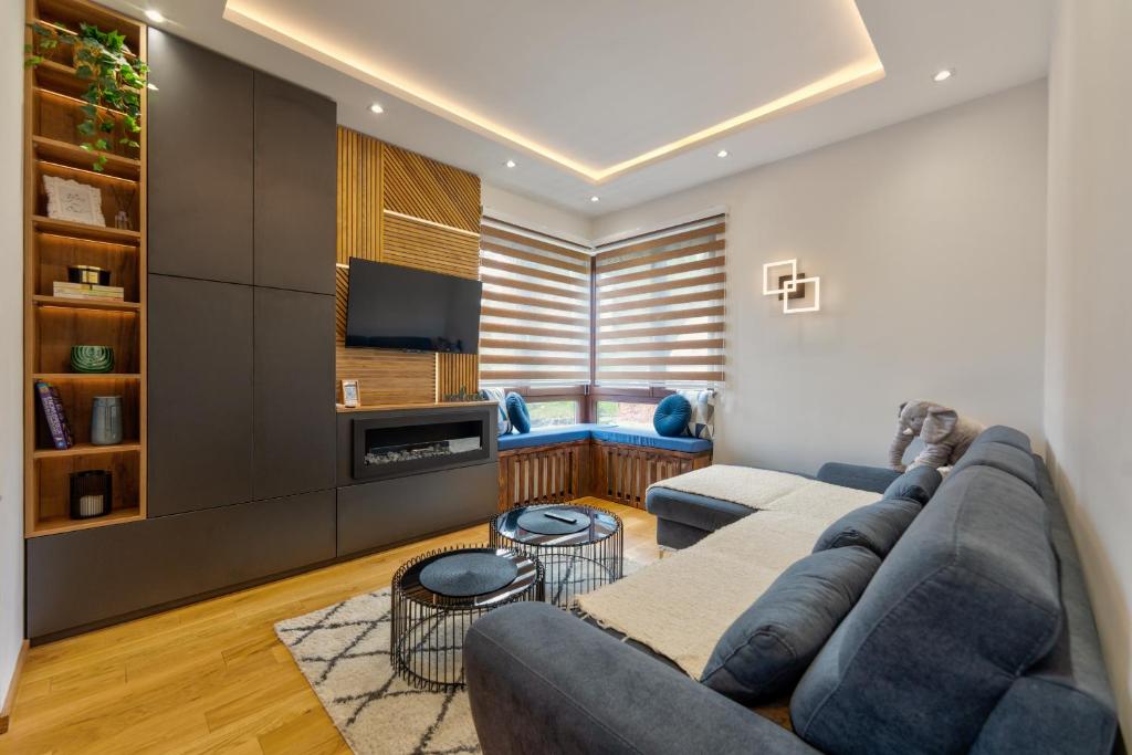 un soggiorno con divano blu e TV di Apartman 1496 a Zlatibor