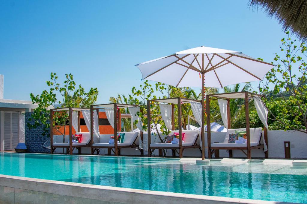 沙由利達的住宿－Sayulinda Hotel，一组椅子和一把遮阳伞,位于游泳池旁