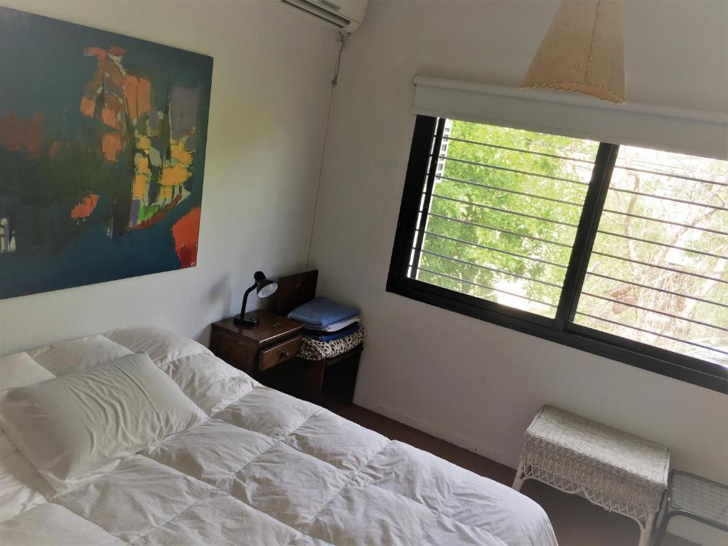 1 dormitorio con cama blanca y ventana en CASA JARDIN HUERTA PILETA Y PARRILLA San Isidro Bs As en San Isidro