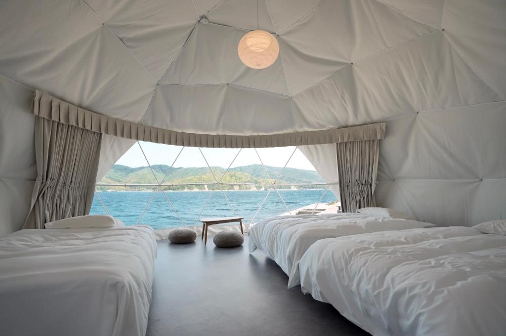 Una fila de camas en una habitación con agua en TADAYOI 海士グランピング, 