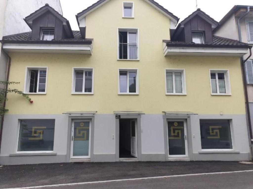 una casa gialla e bianca con finestre e porte di 3 Doppelzimmer Ferienwohnung in Arbon am Bodensee ad Arbon