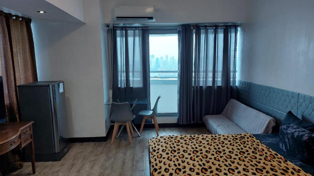 a room with a bed and a couch and a window at MANILA BAY EXECUTIVE SUITE pearl of orient in Manila