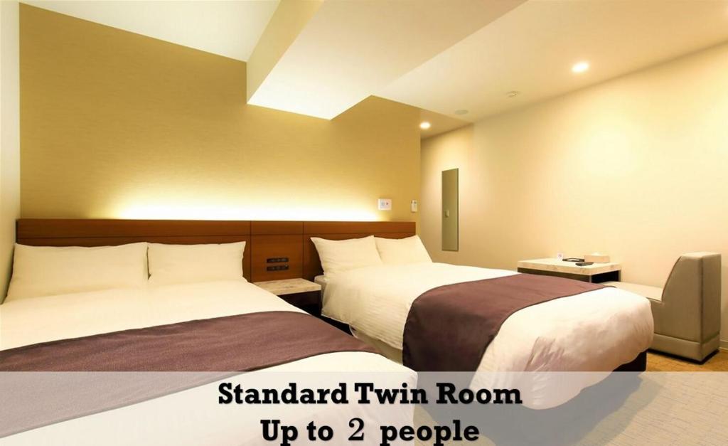 two beds in a hotel room with two people at LUXCARE HOTEL in Osaka