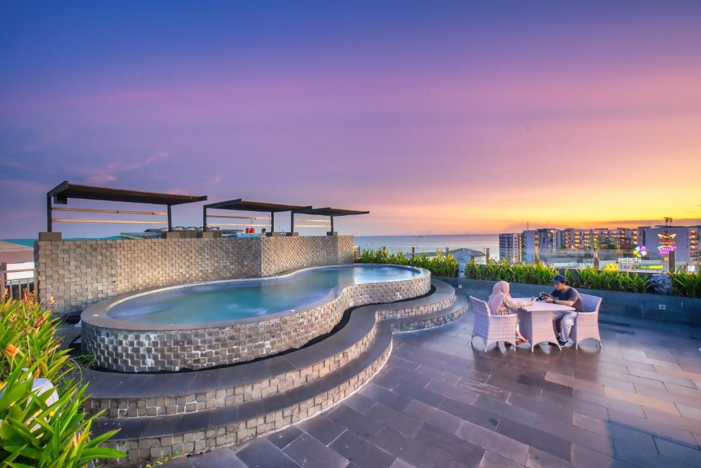 a couple sitting in chairs on a patio with a hot tub at Grand Jatra Hotel Balikpapan in Balikpapan