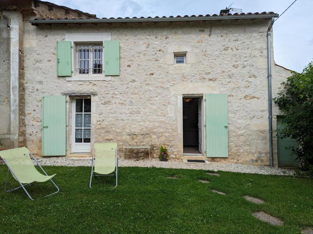 dwa krzesła przed budynkiem z zielonymi okiennicami w obiekcie Maison de Charme avec Jardin, Proche La Rochefoucauld, Wifi, Ping-Pong, et Equipement Bébé - FR-1-653-35 w mieście Bunzac