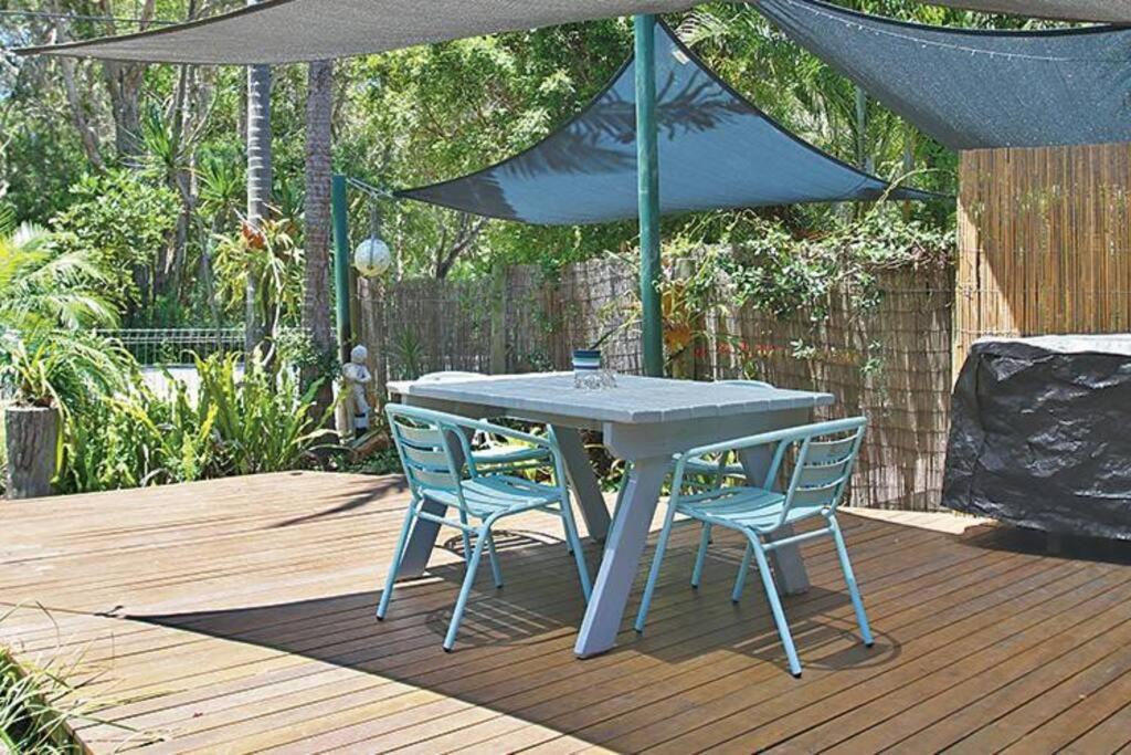 a table and two chairs under an umbrella on a deck at AMITY BEACH BUNGALOW in Amity Point