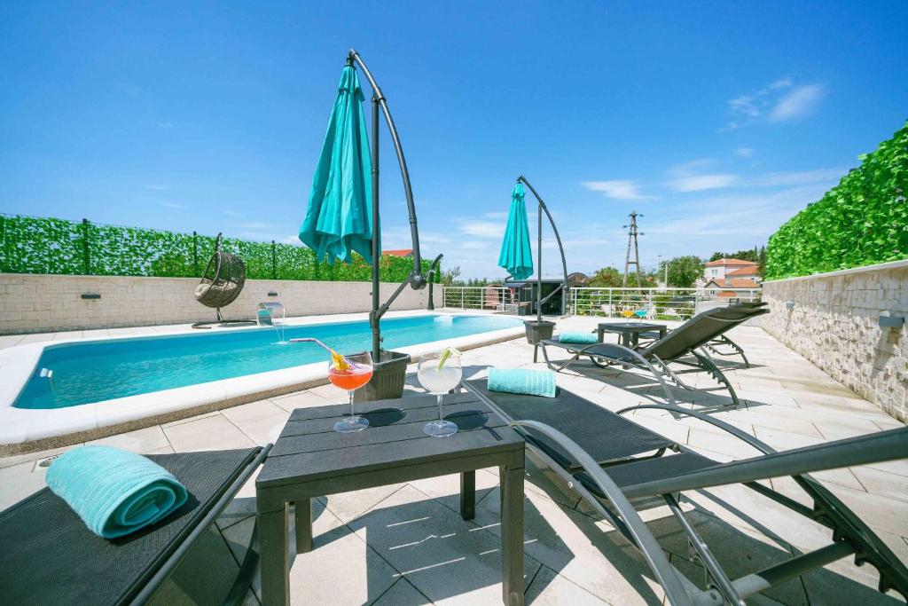 un patio con mesa, sillas y piscina en Villa MyDream en Lađevci