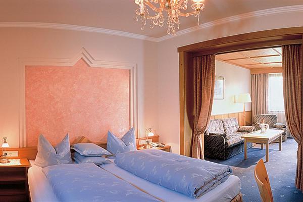a bedroom with a large bed and a living room at Hotel Solstein in Seefeld in Tirol