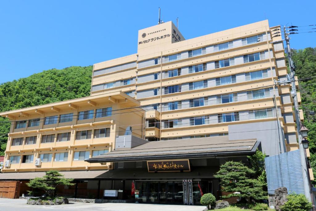 um grande edifício com uma montanha ao fundo em Ashinomaki Grand Hotel em Aizuwakamatsu