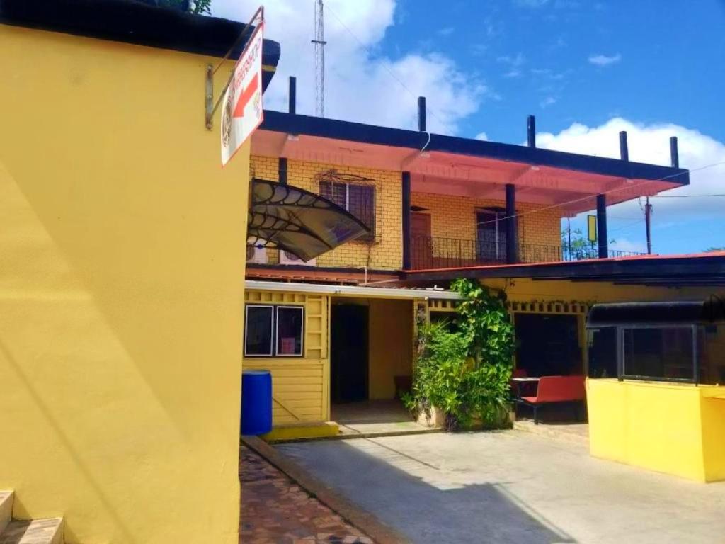 un edificio amarillo con un cartel en el costado en Max Rooms en San Ignacio