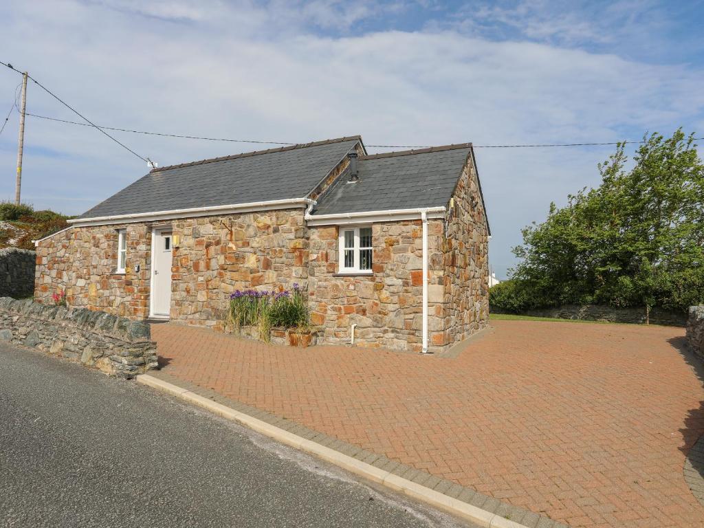 une maison en pierre dans une allée en briques dans l'établissement Tyn Towyn - Bwthyn Carreg, à Trearddur