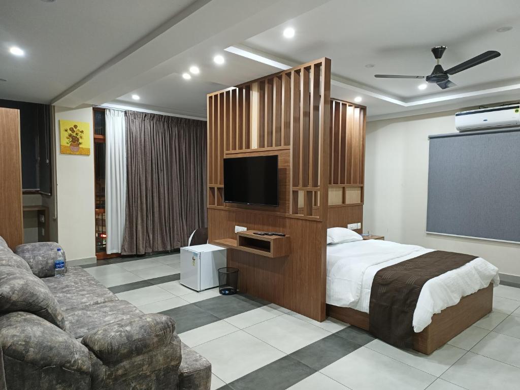 a bedroom with a bed and a flat screen tv at ARAKKAL GUESTHOUSE in Kalpetta