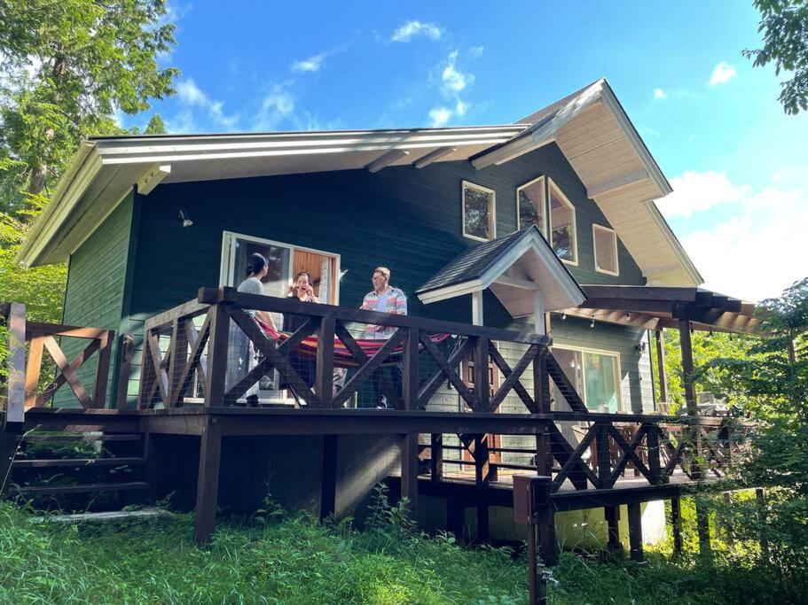 tres personas de pie en el porche de una casa en 4月リニューアルOpen! 全室エアコン完備! Deerview Lodge 山中湖, en Yamanakako