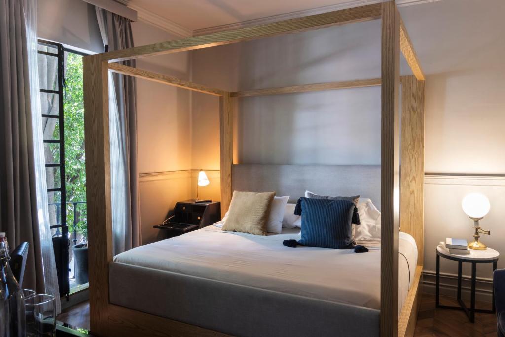 een slaapkamer met een hemelbed met blauwe kussens bij Aposento Boutique Hotel in Mexico-Stad