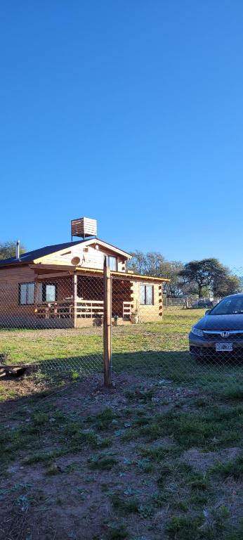 una casa con un coche aparcado delante de ella en Cabaña los ciruelos en Santa Rosa de Calamuchita
