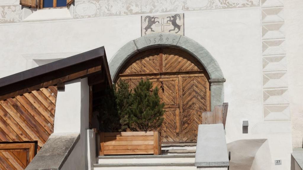 uma entrada para um edifício com uma porta de madeira em Ches'Ota - Verde - La Punt em La Punt-Chamues-ch