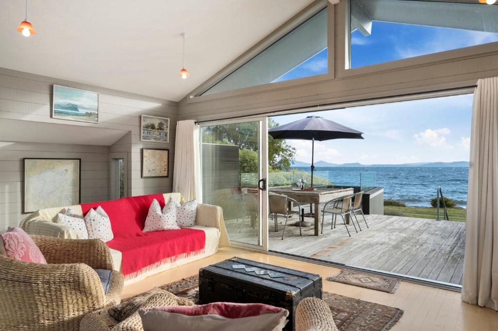 a living room with a red couch and a view of the ocean at Five Mile Bliss - Lake Taupo Holiday Home in Waitahanui