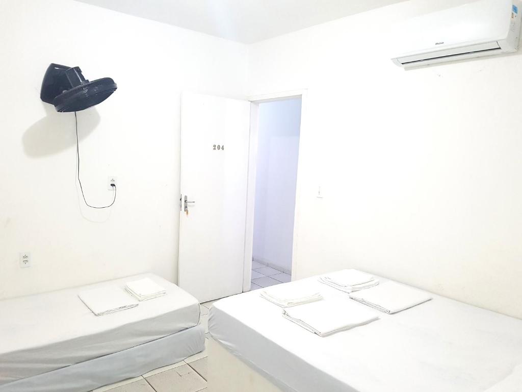 two beds in a room with white walls at Casa Brisa in Fortaleza
