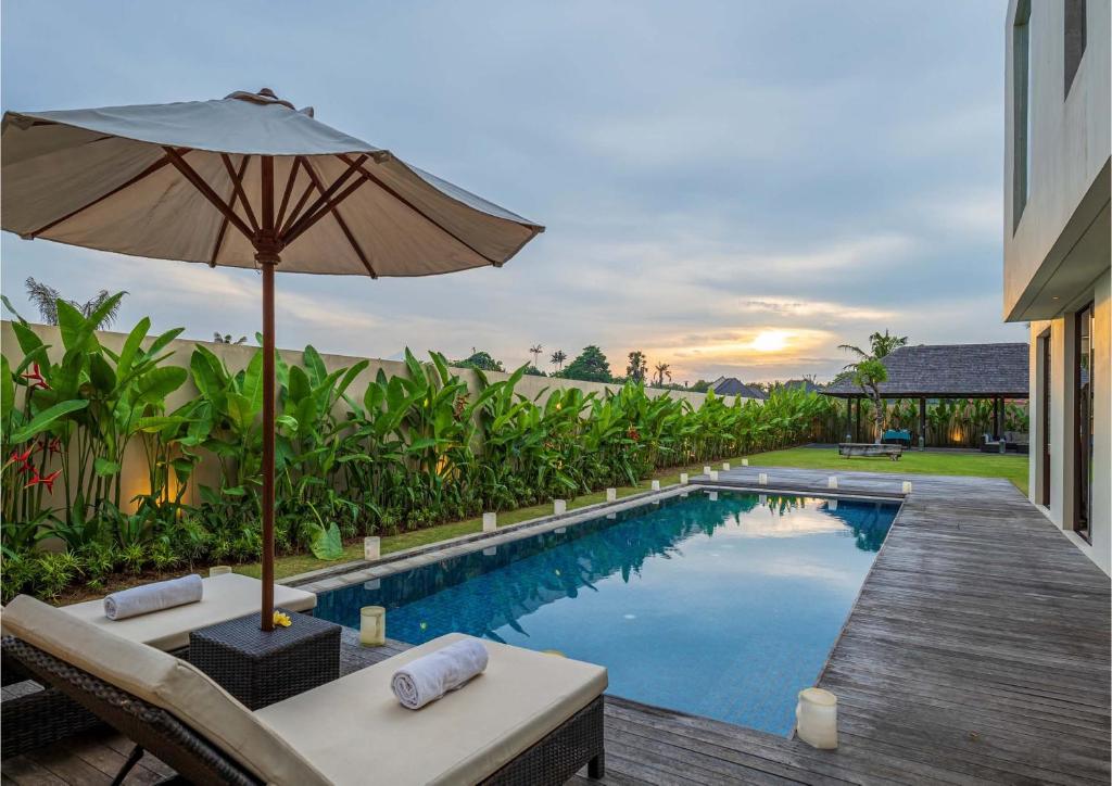 una piscina con sombrilla y sillas y una mesa con sombrilla en Ocean View 3 Bedrooms Brand New Stylish Villa With Private Pool, Gazebo, & Garden, Bali, en Ketewel