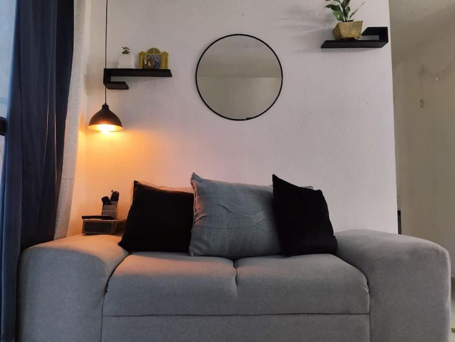 a couch in a living room with a mirror at Departamento Cerca del Aeropuerto/ Buena Ubicación in Mexico City