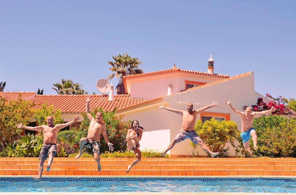 a group of men jumping into a swimming pool at Villa Lagos Algarve for families & friends, 6 bedrooms, 7 bathrooms, pool, BBQ, central heating in Pedra Alçada