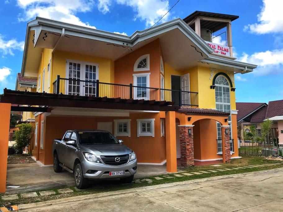 a car parked in front of a yellow and orange house at RPU Wen's Villa in Dauis